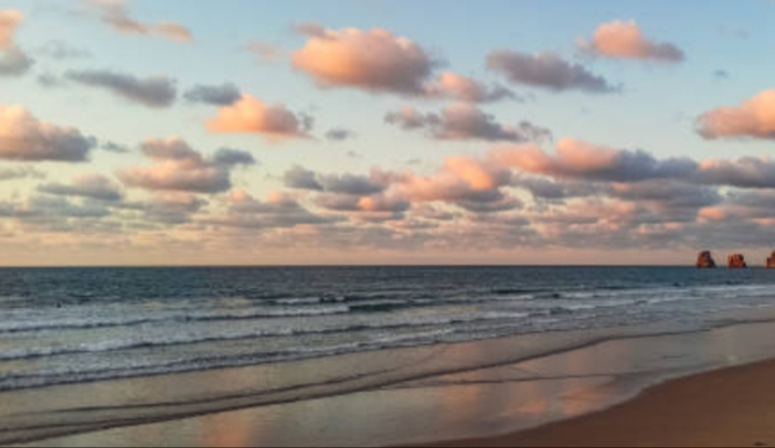 Paysage côtier d'Hendaye au coucher de soleil avec plage, formations rocheuses et ciel nuageux
